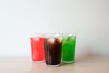 Glasses of soft drink with ice cubes and bubbles on wooden table kitchen background.の写真素材