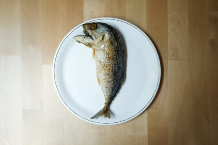 Fried mackerel in white plate on a wooden table, Popular fish menu in Thailand.