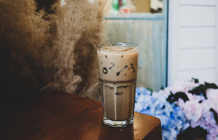 Ice coffee in a tall glass  on a old rustic wooden, cold summer drink on a dark wooden table