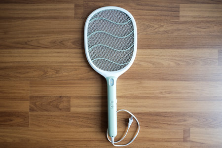 electric mosquito swatter in tennis racket shape style on wooden floor.の写真素材