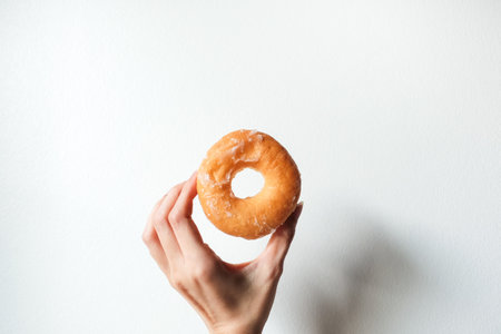 hand holding sweet delicious glazed donut on white background.の写真素材