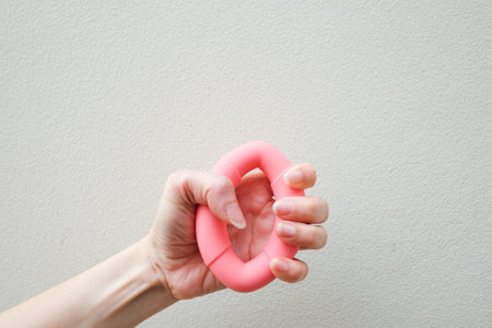 Womanâs hand holding an pink rubber grip or Hand squeezes expander exercise, Sport and fitness concept.の写真素材