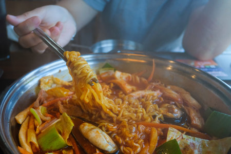 Hot pot of budae jjigae, korean instant noodles (ramyeon), pork,  sausage, mussels and vegetables, delicious Korean food.の写真素材