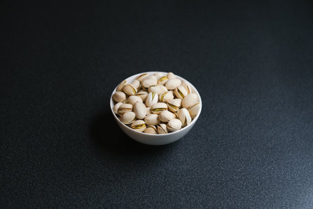 Flat lay of pistachio nuts in white bowl in a morning light and shadow from a window frame.の写真素材