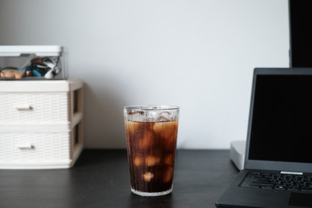 Iced coffee americano in a tall glass at office desk, workplace closeup.の写真素材