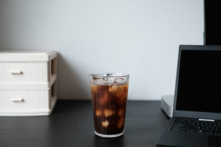 Iced coffee americano in a tall glass at office desk, workplace closeup.