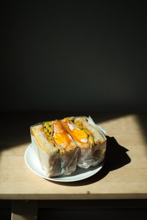 sandwich with filling in paper wrap and light shadow in the morning.
