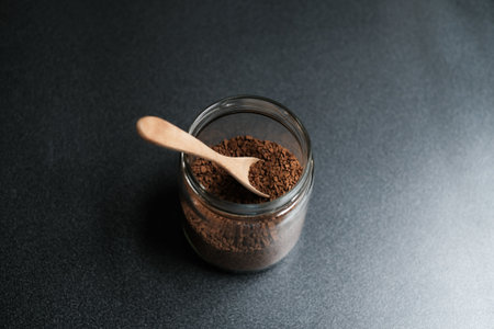 Instant coffee and spoon above glass jar on grey table, top view.の写真素材