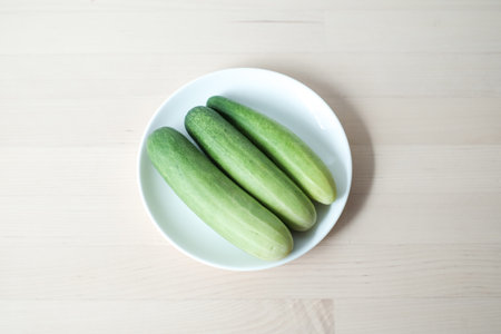 Fresh cucumber in white plate on the wooden table.の写真素材