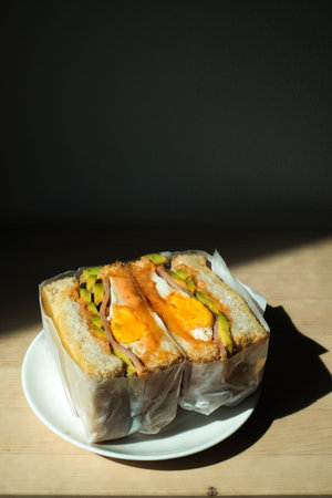 sandwich with filling in paper wrap and light shadow in the morning.の写真素材