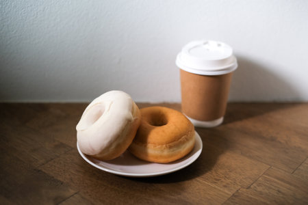 Breakfast donut in white plate and hot coffee on wooden table.の写真素材
