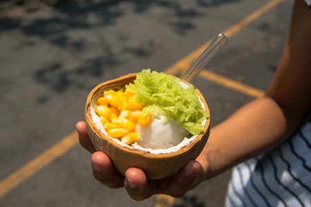 Hand hold Coconut milk icecream in shell with green rice stickの写真素材