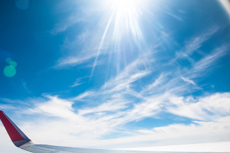 blue sky with airplane wing and sunrayの写真素材