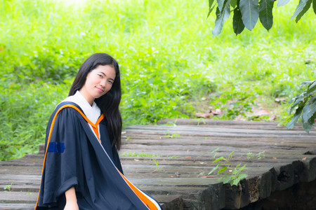 Asian woman in Graduate dress on bridgeの写真素材