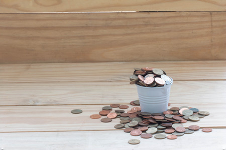 Coin in bucket on wood backgroundconcept saving money