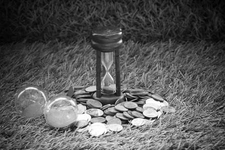 Money Coin and hourglass concept time is money on grassの写真素材