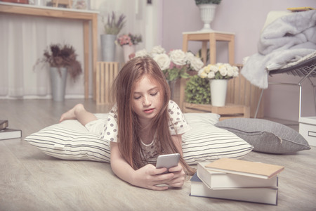 Adorable pretty girl take selfie herself in the living room, a child on FaceTime with friend on mobile, a kid playing game on phoneの写真素材