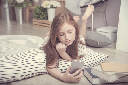 Adorable pretty girl take selfie herself in the living room, daughter on FaceTime with father on mobileの写真素材