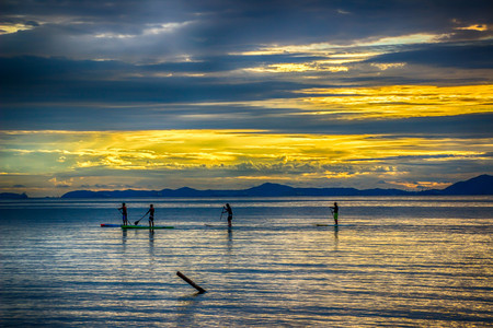 Evening sea, sky with yellow clouds, sunset, tourists are rowing in the sea.
