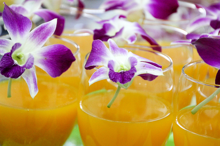 Orange juice prepared to wait for customers on glass decorated with orchids.の写真素材