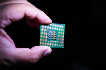 Computer CPUs in the hands of men on a black background.の写真素材