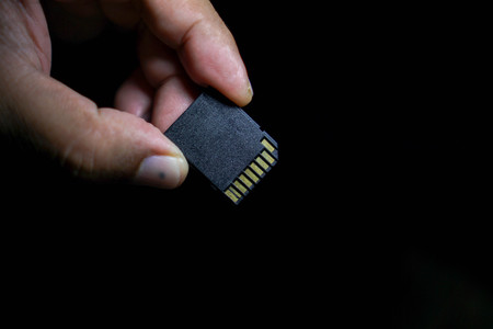 SD Cards in hand on a black background.