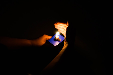 Candle flame at night with bokeh on dark background with go light Blessed is the light of holiness...
