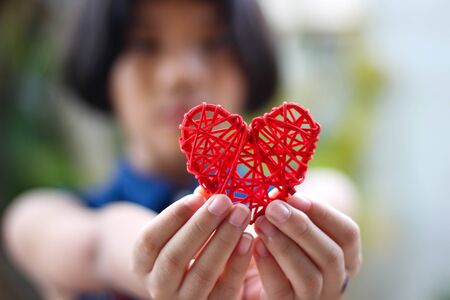 The red heart is on the girl's hand.の写真素材