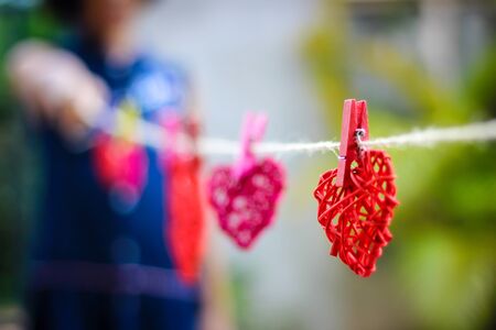 The red rattan heart hung with a child holding the other end of the rope.