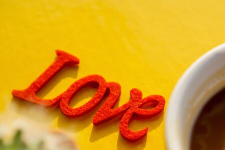 The red love is on the yellow table and blur some coffee mugs.
