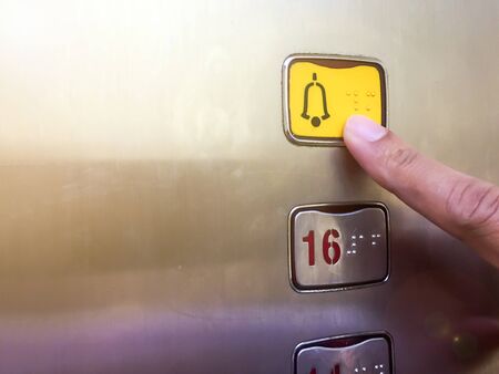 The emergency button in the lift is being pressed by a man's hand in an emergency.