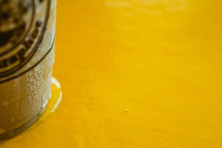 Coffee cup with water attached to the cup because all the coolness is on a yellow wooden table.