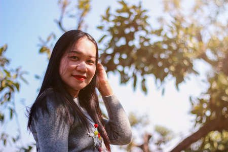 Asian women in Thailand smiling and with natural bokeh background.