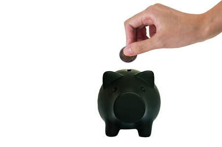 Hand putting coin into the piggy bank one black smiling money pig isolated on white background 