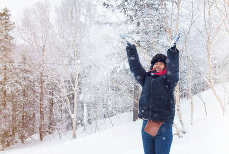Happy woman plays with a snow in sunny winter dayの写真素材