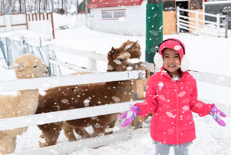 Happy girl plays with a snow in sunny winter dayの写真素材