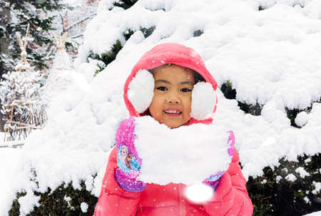 Happy girl plays with a snow in sunny winter dayの写真素材
