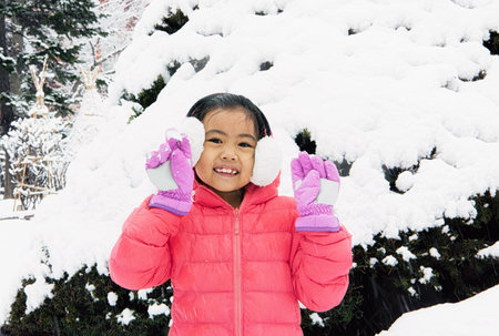 Happy girl plays with a snow in sunny winter dayの写真素材