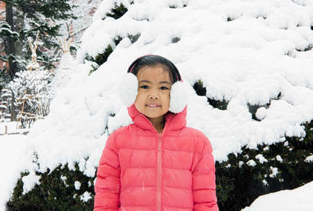 Happy girl plays with a snow in sunny winter dayの写真素材