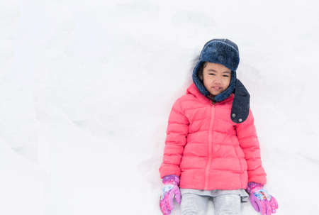 Happy girl plays with a snow in sunny winter dayの写真素材