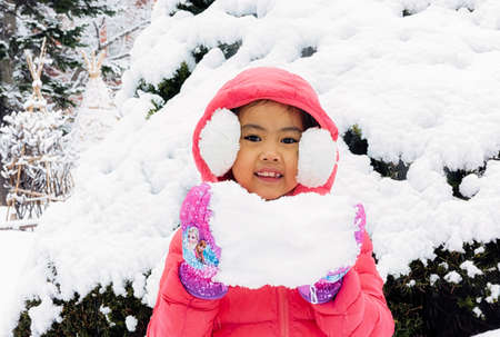 Happy girl plays with a snow in sunny winter dayの写真素材