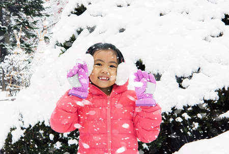 Happy girl plays with a snow in sunny winter dayの写真素材