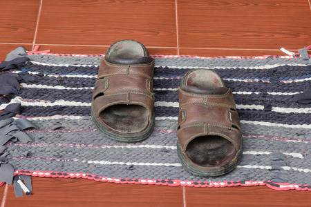 Old sandals on doormatの写真素材