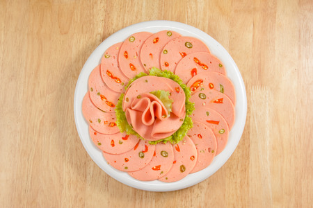 Spicy bologna in a white dish on wood tabletop