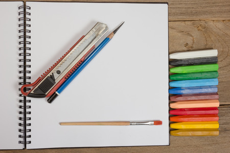 notebook and colorful crayons on wooden background.の写真素材
