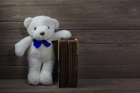 Teddy bear with old book on wood background, still lifeの写真素材