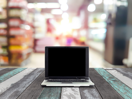 laptops on desk with blur shelves in supermarket backgroundの写真素材