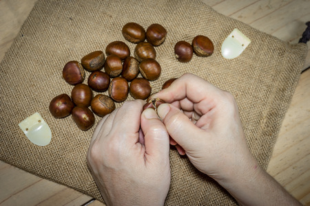 hand holding fresh chestnuts with sack bag backgroundの写真素材