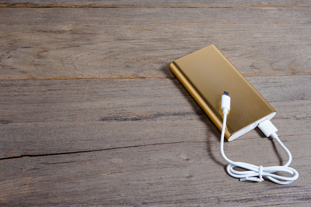 Golden powerbank on wood backgroundの写真素材