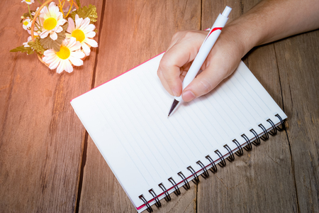 Human hand holding pen with open note bookの写真素材